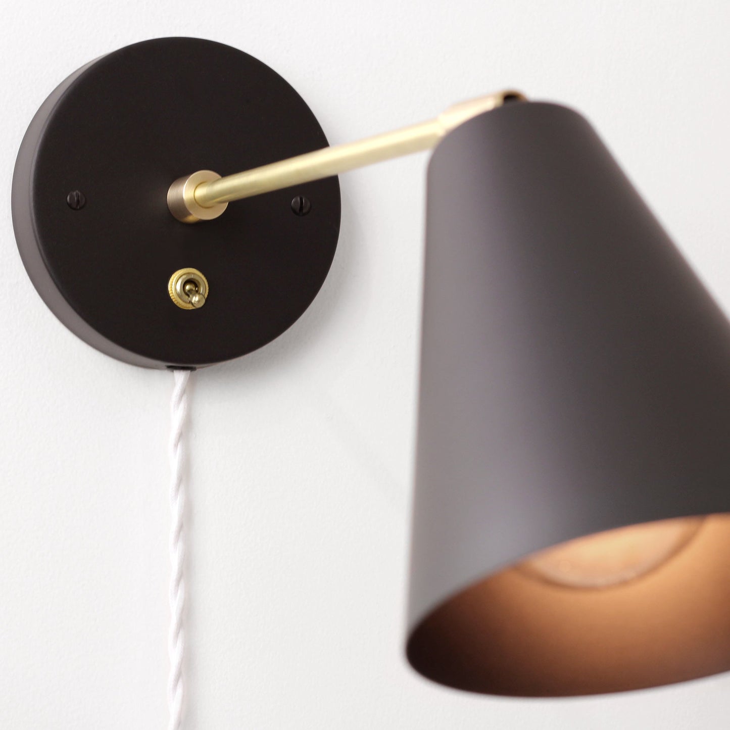 Cedar and Moss. Tilt Cone - 9" arm. Shown in Matte Black + Brass with Brass switch and white cord.